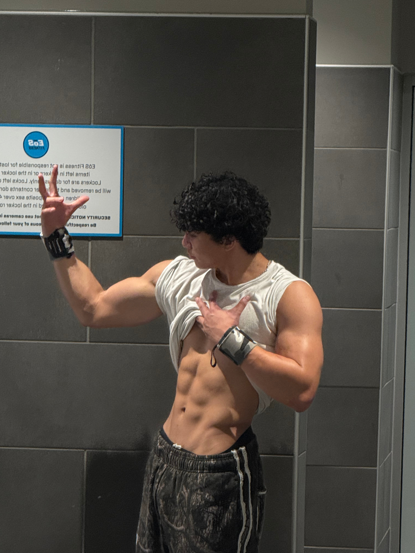 Mid transformation — front pose with visible abs and arm growth in the gym
