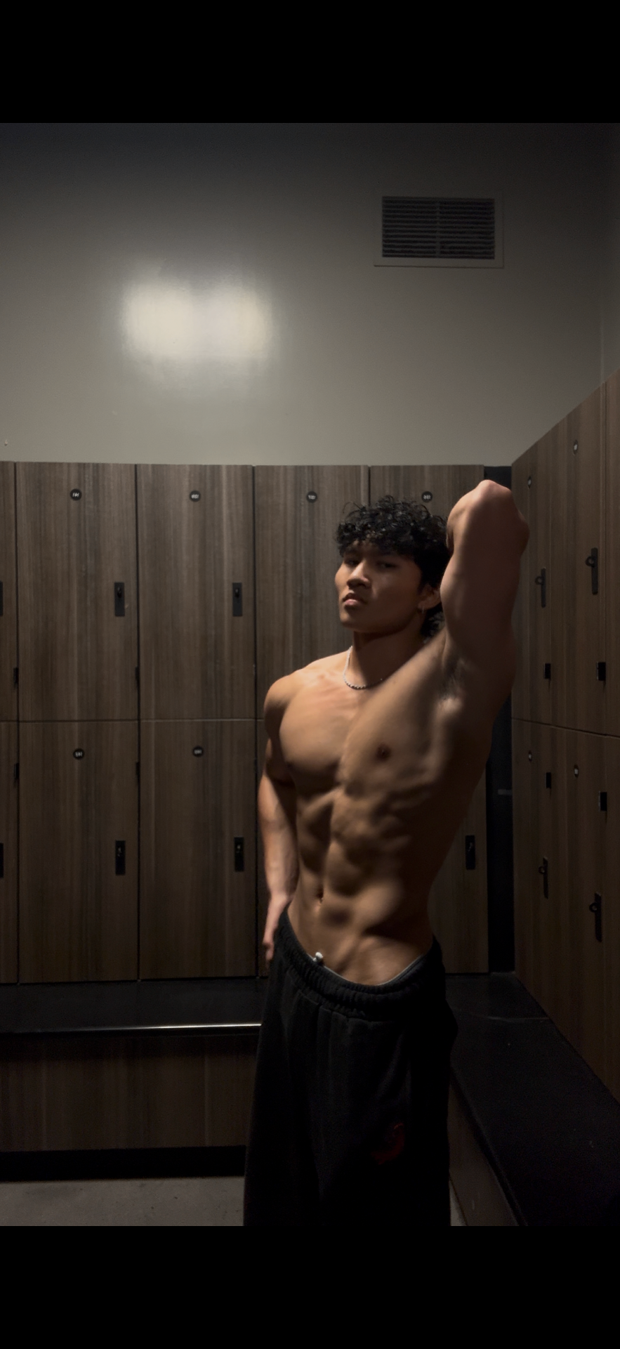 Peak transformation — 175 lb side physique pose in gym locker room