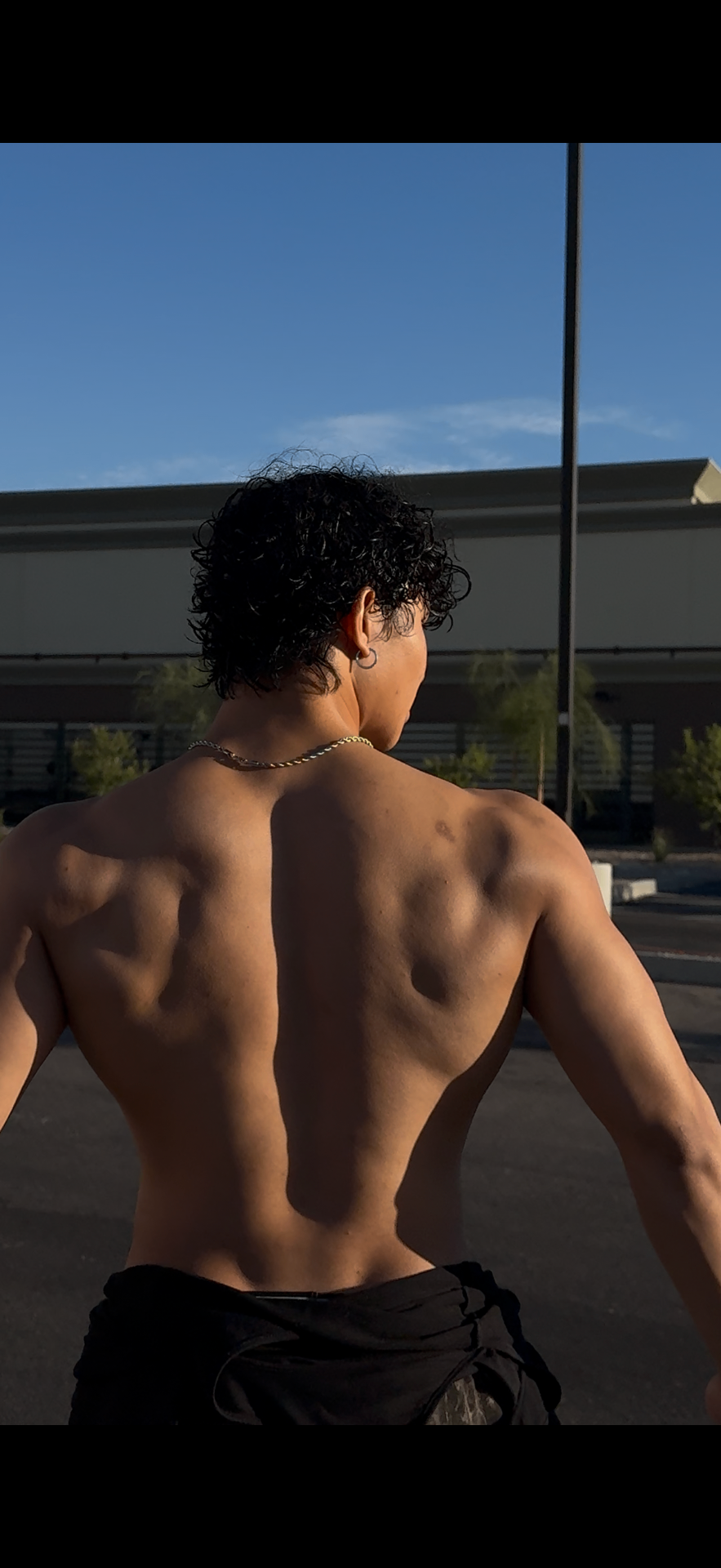 Rear back double biceps pose in golden hour light outdoors
